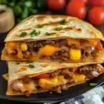 Stacked beef quesadillas filled with melted cheddar, corn, and bell peppers in grilled tortillas