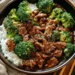 Bowl of teriyaki beef and broccoli served over white rice, topped with sesame seeds