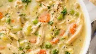Delicious chicken pot pie soup in a bowl with fresh herbs and vegetables