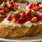 Strawberry Ricotta Bruschetta topped with fresh strawberries and mint on a toasted slice of bread